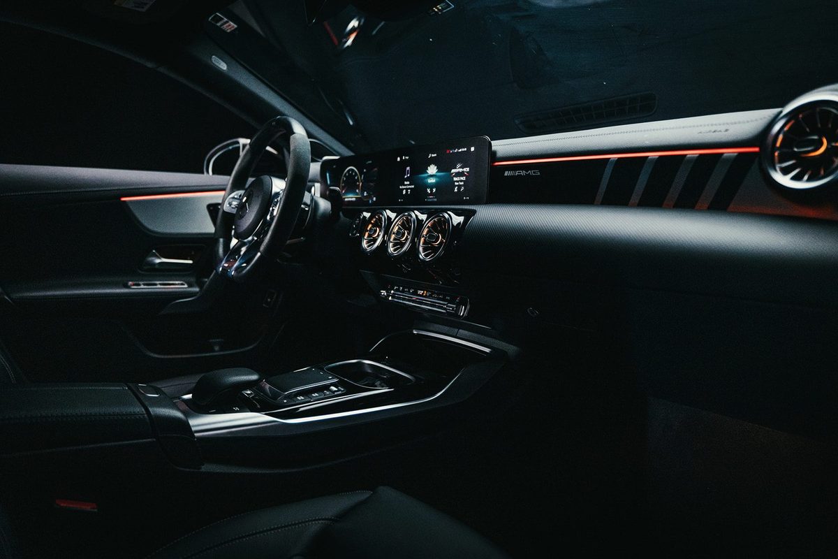 Mercedes AMG cabin at night, red ambient lighting tracing the dashboard and digital cockpit