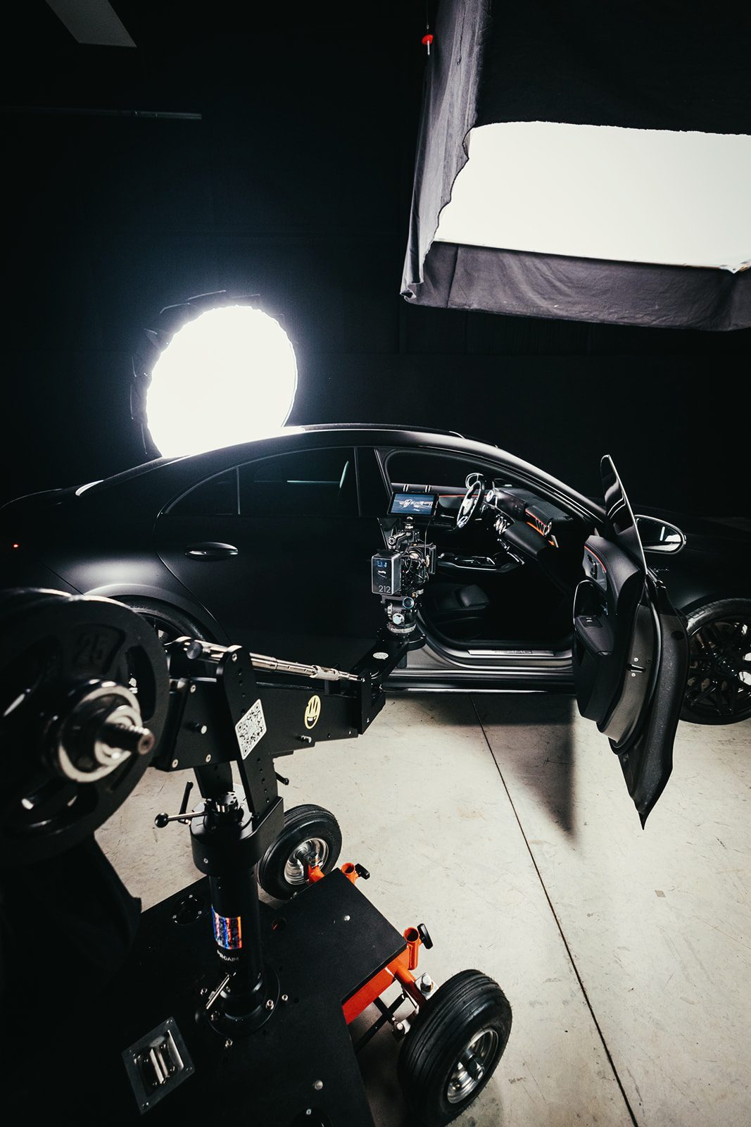 Camera dolly beside an open car door with studio lights behind