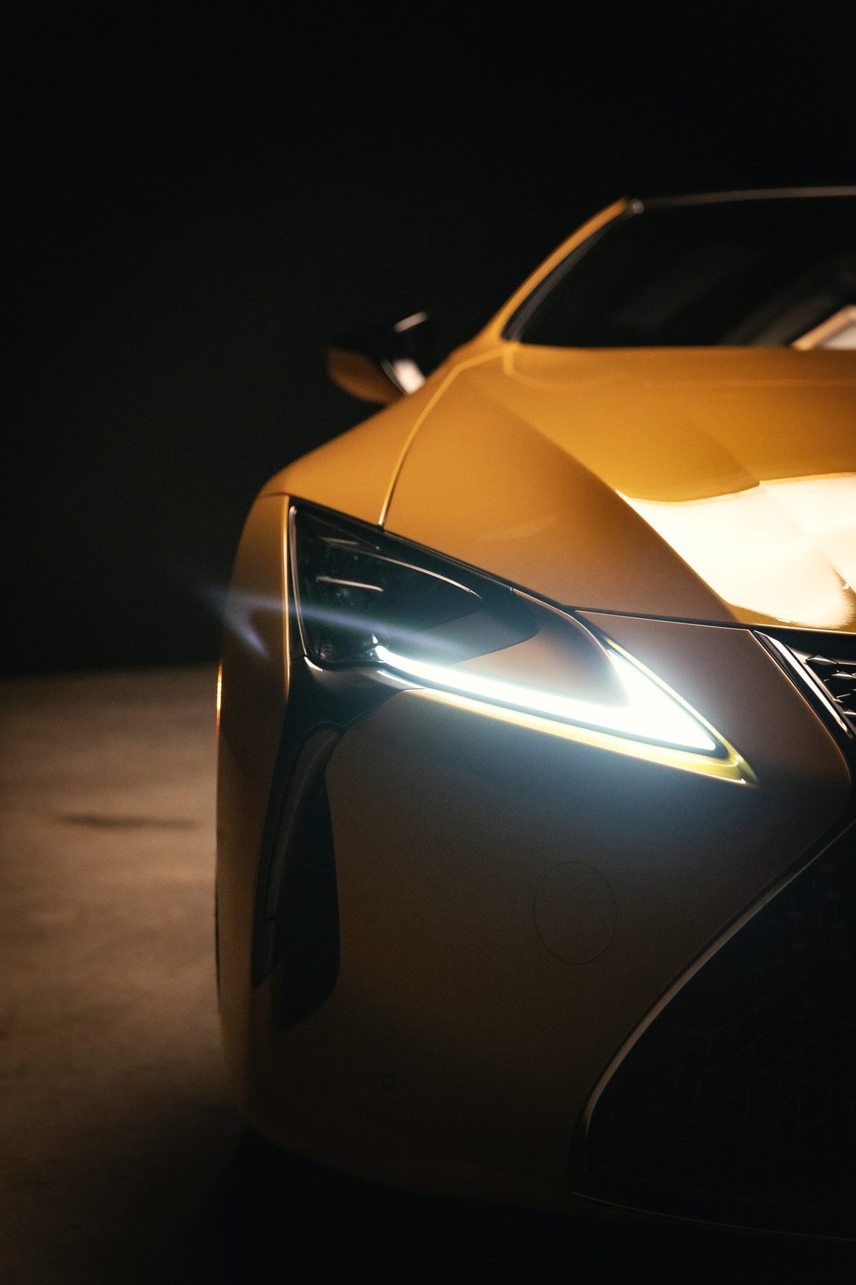 LC 500 front corner with its headlight glowing in the dark